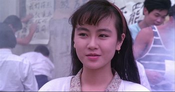 Movie still from “Bullet in the Head” (1990), directed by John Woo – A young woman with long black hair wearing a white shirt; Close Up shot, Low angle
