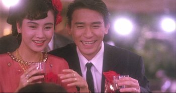 Movie still from “Bullet in the Head” (1990), directed by John Woo – A man and a woman smiling for a picture; Close Up shot, High angle