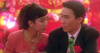 Movie still from “Bullet in the Head” (1990), directed by John Woo – A man and a woman sitting next to each other at a table; Close Up shot, Over the shoulder angle