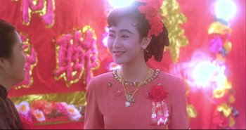 Movie still from “Bullet in the Head” (1990), directed by John Woo – A woman in a pink dress and a red flower in her hair; Close Up shot, High angle
