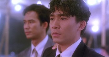 Movie still from “Bullet in the Head” (1990), directed by John Woo – A man in a suit and tie looking at the camera; Close Up shot, Low angle