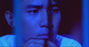 Movie still from “Bullet in the Head” (1990), directed by John Woo – A person with his hand under his chin; Close Up shot, High angle