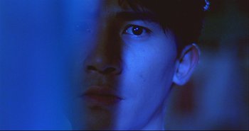 Movie still from “Bullet in the Head” (1990), directed by John Woo – A young man with blue eyes stares into the camera; Extreme Close Up shot, Low angle