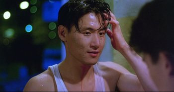Movie still from “Bullet in the Head” (1990), directed by John Woo – A young man with wet hair is looking at the camera; Close Up shot, High angle
