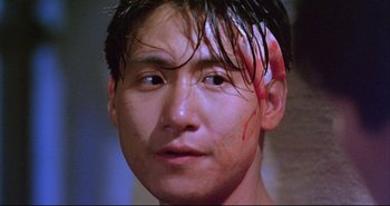 Movie still from “Bullet in the Head” (1990), directed by John Woo – A person with blood on his face; Close Up shot, Low angle