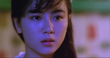 Movie still from “Bullet in the Head” (1990), directed by John Woo – A young woman's face in a purple light; Close Up shot, High angle