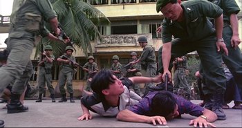 Movie still from “Bullet in the Head” (1990), directed by John Woo – A group of people fighting in front of a building; Wide shot, High angle