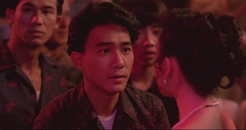 Movie still from “Bullet in the Head” (1990), directed by John Woo – A group of young men and women in a room; Close Up shot, Over the shoulder angle