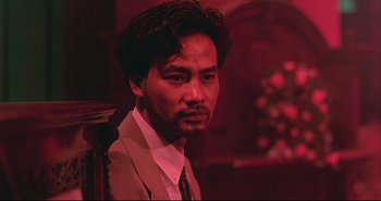 Movie still from “Bullet in the Head” (1990), directed by John Woo – A person wearing a suit and tie; Close Up shot, Low angle