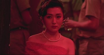 Movie still from “Bullet in the Head” (1990), directed by John Woo – A woman in a red dress and a pearl necklace; Close Up shot, Over the shoulder angle