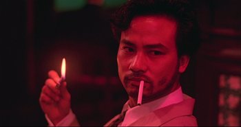 Movie still from “Bullet in the Head” (1990), directed by John Woo – A man holding a lit cigarette in his mouth; Close Up shot, Low angle
