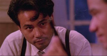 Movie still from “Bullet in the Head” (1990), directed by John Woo – A person wearing a suit and tie; Close Up shot, Over the shoulder angle