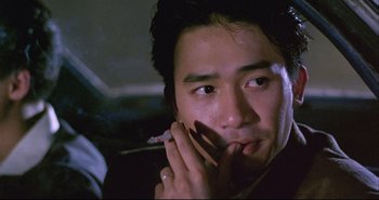 Movie still from “Bullet in the Head” (1990), directed by John Woo – A person holding a cell phone to his ear; Close Up shot, Low angle