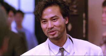 Movie still from “Bullet in the Head” (1990), directed by John Woo – A person wearing a suit and tie; Close Up shot, Low angle