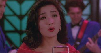 Movie still from “Bullet in the Head” (1990), directed by John Woo – A woman's face in a red dress; Close Up shot, Over the shoulder angle