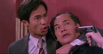 Movie still from “Bullet in the Head” (1990), directed by John Woo – Two asian men in business suits and ties; Close Up shot, Low angle
