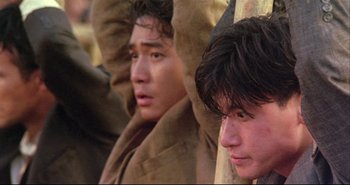 Movie still from “Bullet in the Head” (1990), directed by John Woo – Two young men are sitting next to each other; Close Up shot, Low angle