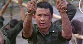 Movie still from “Bullet in the Head” (1990), directed by John Woo – A man holding a rope with blood all over his face; Medium shot, High angle