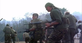 Movie still from “Bullet in the Head” (1990), directed by John Woo – A group of men in fatigues are walking through the woods; Medium shot, Low angle