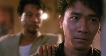 Movie still from “Bullet in the Head” (1990), directed by John Woo – Two men are sitting in front of each other; Close Up shot, Over the shoulder angle