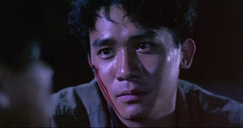 Movie still from “Bullet in the Head” (1990), directed by John Woo – A person with blood on his face; Close Up shot, Low angle