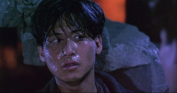 Movie still from “Bullet in the Head” (1990), directed by John Woo – A young man with a wet face sitting in a chair; Close Up shot, High angle