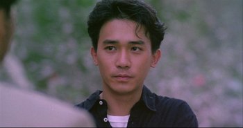 Movie still from “Bullet in the Head” (1990), directed by John Woo – A person wearing a black shirt; Close Up shot, High angle