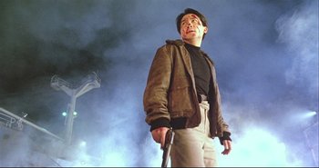 Movie still from “Bullet in the Head” (1990), directed by John Woo – A man standing in the fog holding a baseball bat; Medium shot, Low angle