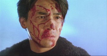 Movie still from “Bullet in the Head” (1990), directed by John Woo – A person with blood all over his face; Close Up shot, High angle