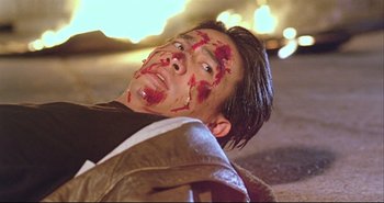 Movie still from “Bullet in the Head” (1990), directed by John Woo – A man with blood all over his face; Close Up shot, High angle