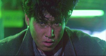 Movie still from “Bullet in the Head” (1990), directed by John Woo – A young man with green eyes and a black jacket; Close Up shot, Low angle