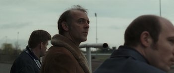 Movie still from “Bullhead” (2011), directed by Michaël R. Roskam – A person wearing a fur coat; Close Up shot, Over the shoulder angle