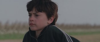 Movie still from “Bullhead” (2011), directed by Michaël R. Roskam – A young boy is sitting in the grass; Close Up shot, Low angle