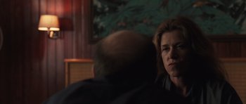 Movie still from “Bullhead” (2011), directed by Michaël R. Roskam – A woman sitting in front of a man in front of a painting; Close Up shot, Over the shoulder angle