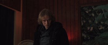 Movie still from “Bullhead” (2011), directed by Michaël R. Roskam – A man with long blonde hair wearing a black jacket; Medium shot, Low angle