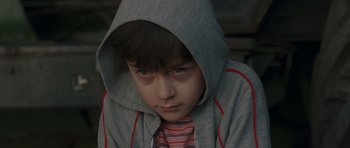 Movie still from “Bullhead” (2011), directed by Michaël R. Roskam – A young boy wearing a hooded jacket looking sad; Close Up shot, High angle
