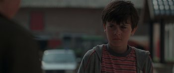 Movie still from “Bullhead” (2011), directed by Michaël R. Roskam – A young boy standing in front of a building; Close Up shot, Low angle