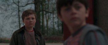 Movie still from “Bullhead” (2011), directed by Michaël R. Roskam – Two young boys standing next to each other in a wooded area; Close Up shot, Over the shoulder angle