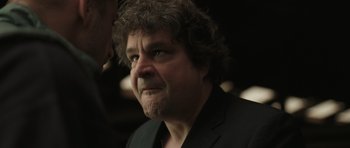 Movie still from “Bullhead” (2011), directed by Michaël R. Roskam – A person wearing a suit and tie; Close Up shot, Over the shoulder angle