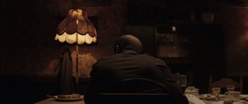 Movie still from “Bullhead” (2011), directed by Michaël R. Roskam – A man sitting in front of a lamp in a dark room; Medium shot, Over the shoulder angle