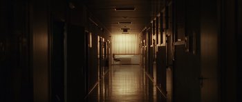 Movie still from “Bullhead” (2011), directed by Michaël R. Roskam – A long hallway with a desk and chair in it; Extreme Wide shot, Low angle