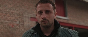 Movie still from “Bullhead” (2011), directed by Michaël R. Roskam – A person wearing a green jacket; Close Up shot, Low angle