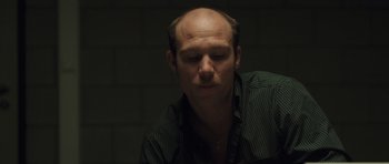 Movie still from “Bullhead” (2011), directed by Michaël R. Roskam – A man with a bald head is looking down; Close Up shot, High angle