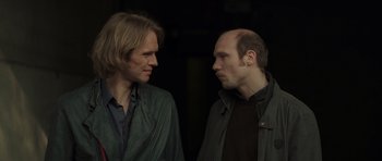 Movie still from “Bullhead” (2011), directed by Michaël R. Roskam – A couple of men standing next to each other; Close Up shot, Over the shoulder angle