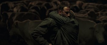 Movie still from “Bullhead” (2011), directed by Michaël R. Roskam – A man hugging another man in a green jacket; Medium shot, Over the shoulder angle