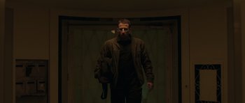 Movie still from “Bullhead” (2011), directed by Michaël R. Roskam – A man is walking in the dark holding a bag; Medium shot, Low angle