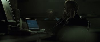 Movie still from “Bullhead” (2011), directed by Michaël R. Roskam – A man sitting at a table talking on the phone; Medium shot, Over the shoulder angle