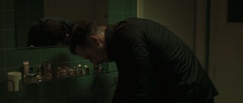 Movie still from “Bullhead” (2011), directed by Michaël R. Roskam – A man in a black shirt is in a bathroom; Medium shot, Low angle