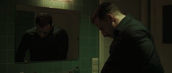 Movie still from “Bullhead” (2011), directed by Michaël R. Roskam – A man standing in front of a mirror in a bathroom; Medium shot, Low angle