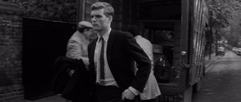 Movie still from “Bunny Lake Is Missing” (1965), directed by Otto Preminger – Black and white photograph of a man in a suit; Medium shot, Low angle